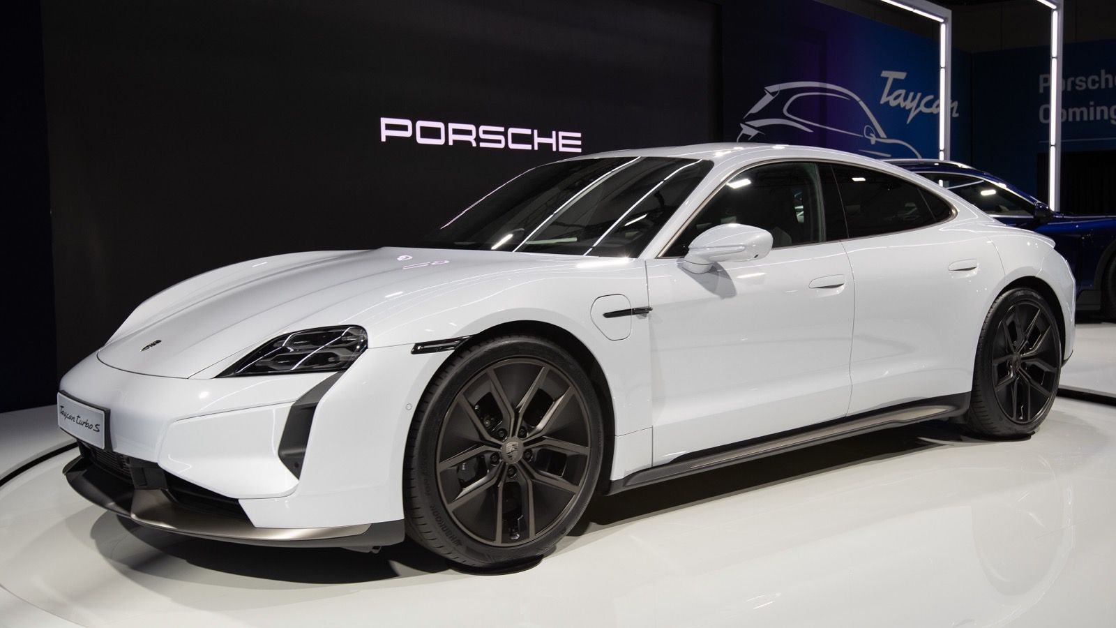 White 2024 Porsche Taycan Turbo S on an auto-show stand, front three-quarter view