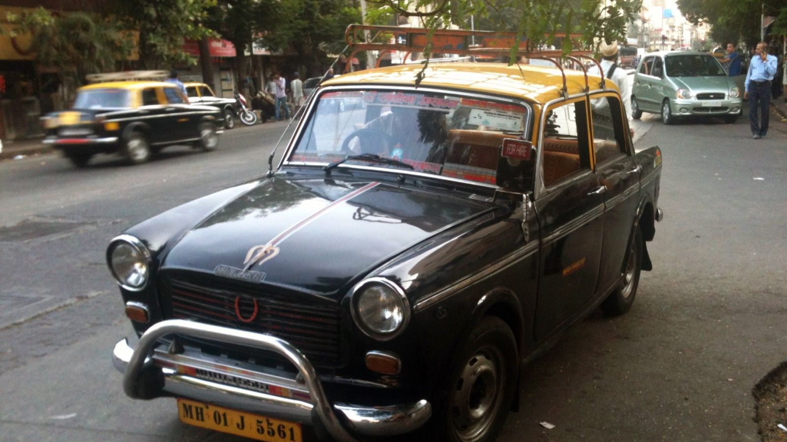 Black-and-yellow Premier Padmini taxi on a Mumbai street, front three-quarter view
