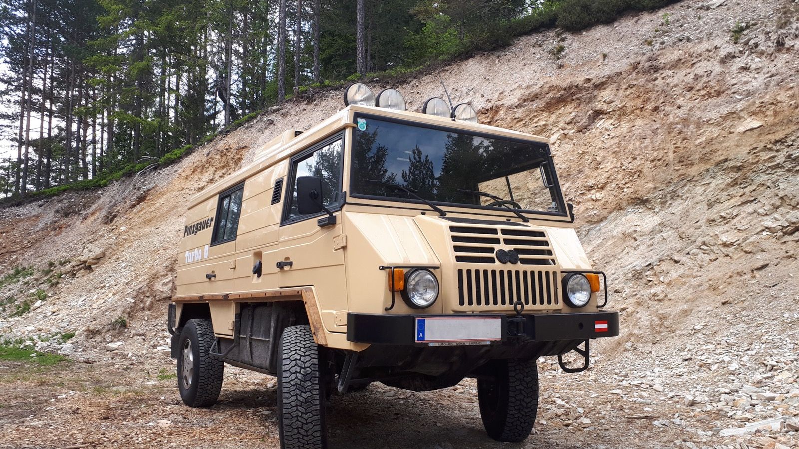 Sand-coloured Steyr-Puch Pinzgauer Turbo D on a gravel track, front three-quarter view