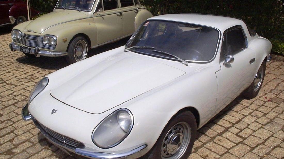 White 1967 Puma GT coupe, front three-quarter view on a brick driveway with a DKW saloon behind