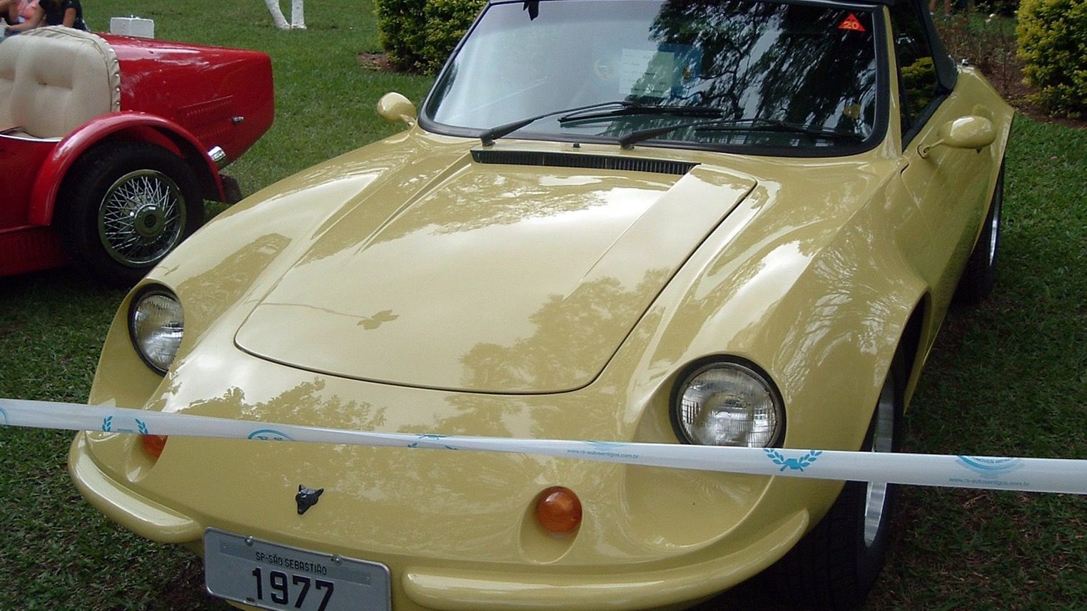 Pale yellow 1977 Puma GTS 1600 roadster with black soft top, front three-quarter view at a Brazilian classic car show