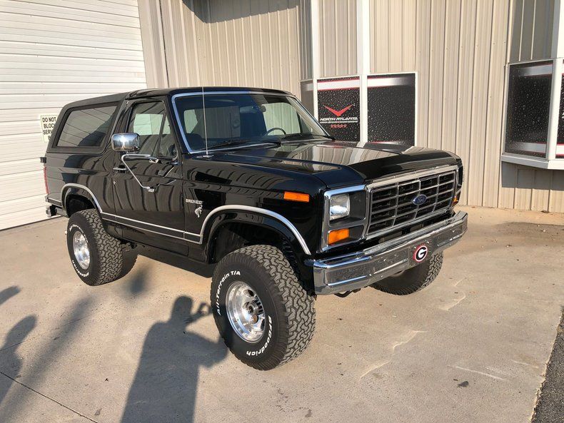 1983 Ford Bronco, black full-size SUV with raised stance and aftermarket wheels, front three-quarter view