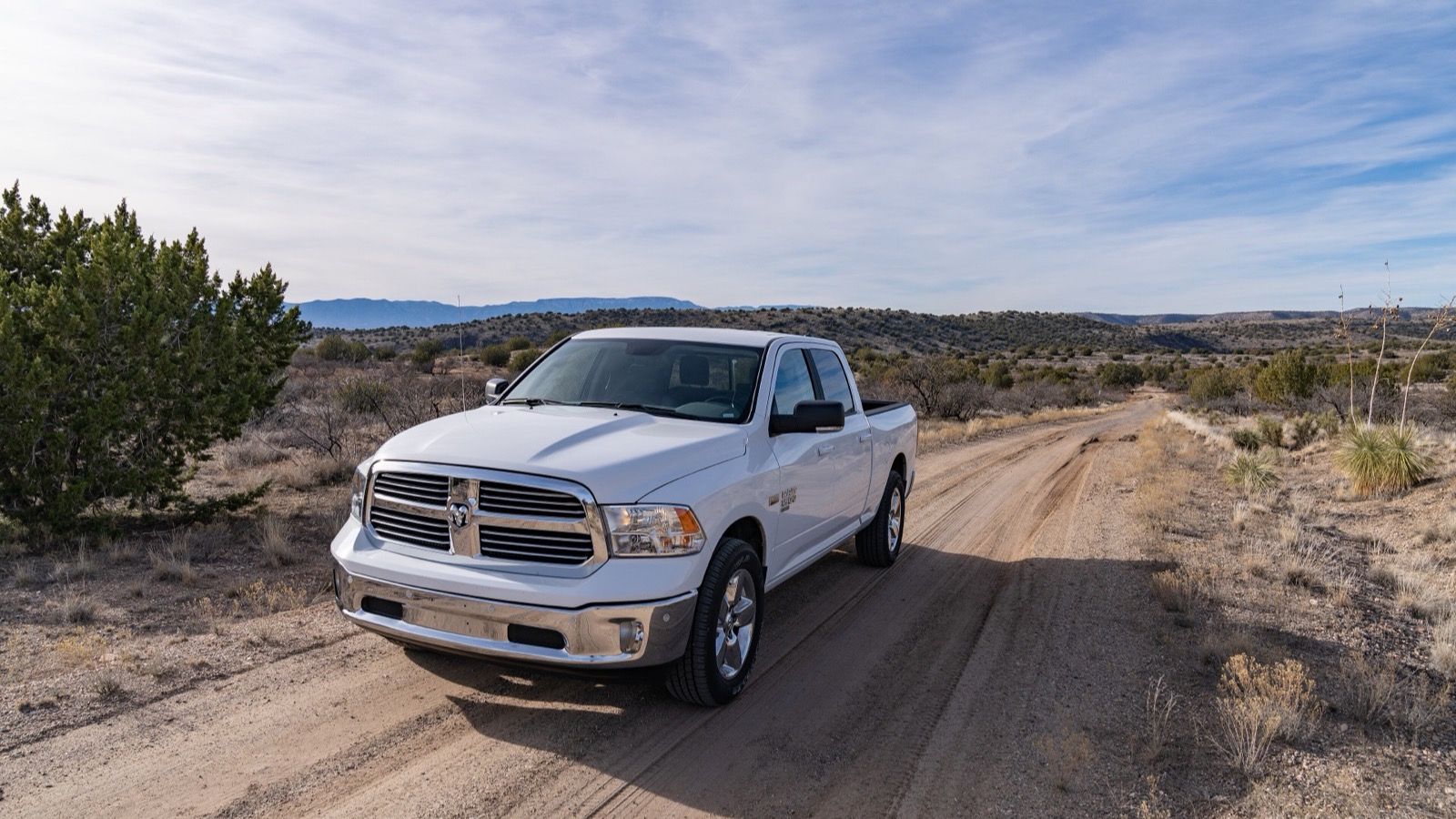 White fourth-generation (DS) Ram 1500 crew cab on a desert dirt road, front three-quarter view
