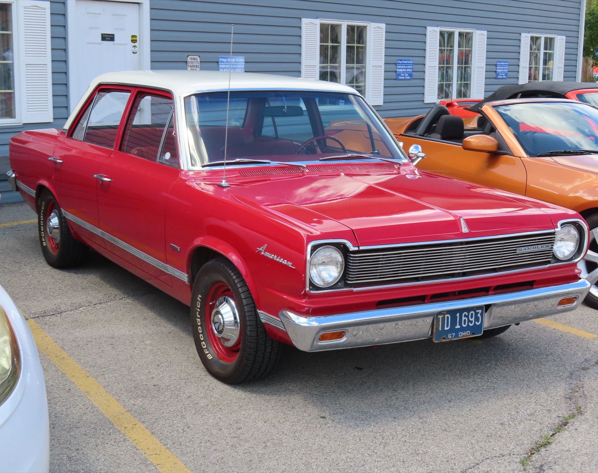 Red 1967 Rambler American 440 four-door sedan with white roof, front three-quarter view