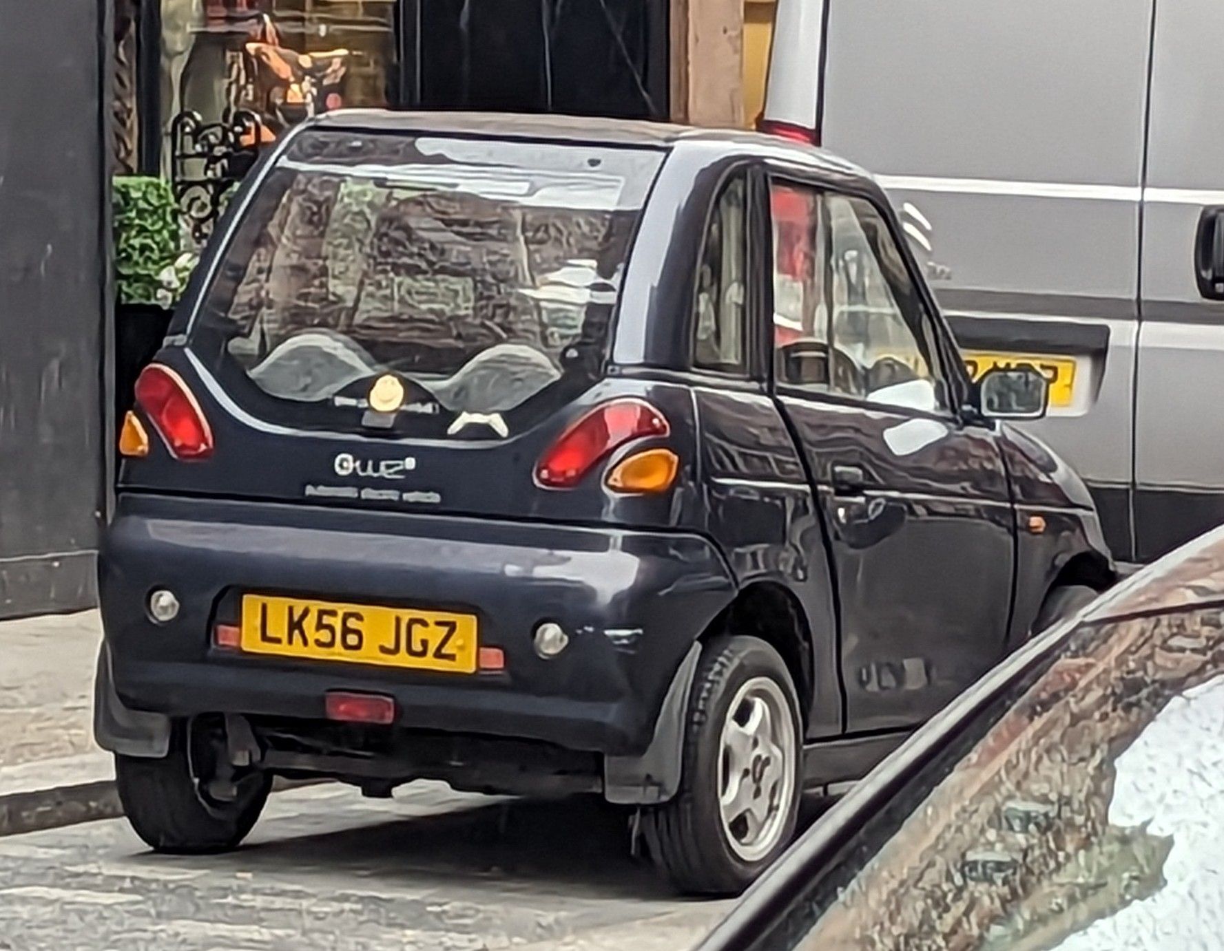 Dark blue REVA G-Wiz microcar parked on a London street, rear three-quarter view