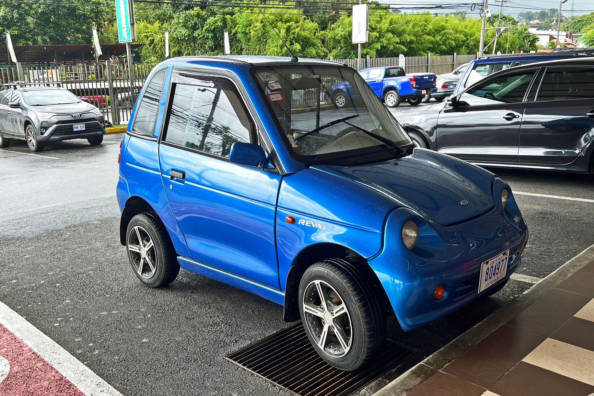 Blue REVAi electric microcar parked at a kerb in Costa Rica, front three-quarter view