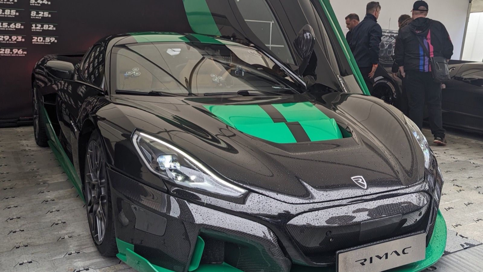 2023 Rimac Nevera in black with green accents, doors raised, front three-quarter view