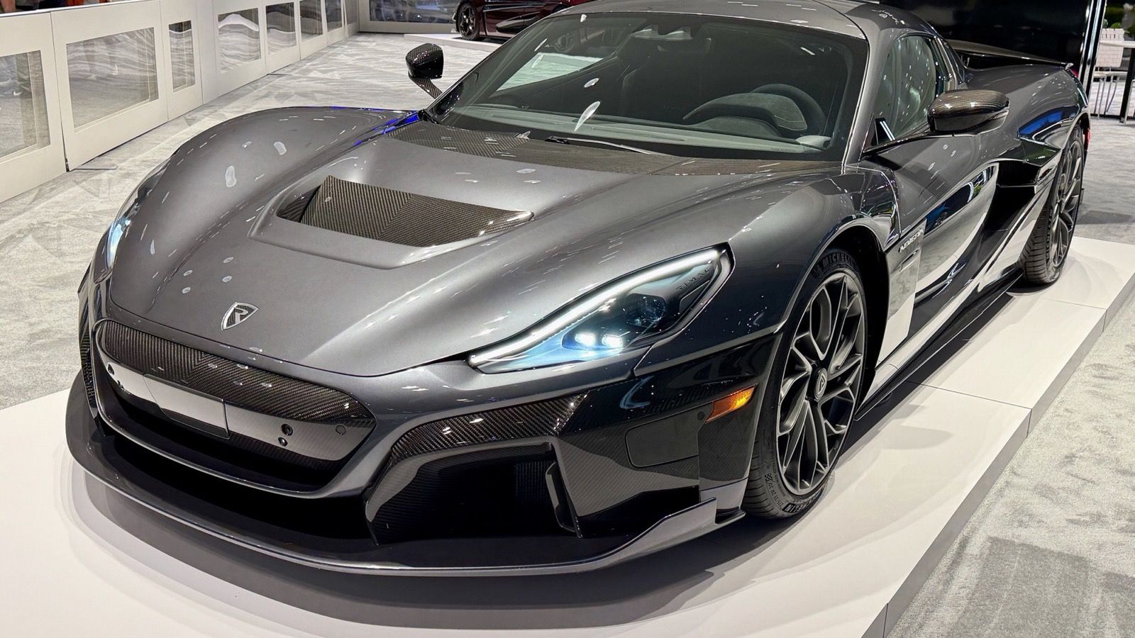 2025 Rimac Nevera in grey on an auto-show stand, front three-quarter view