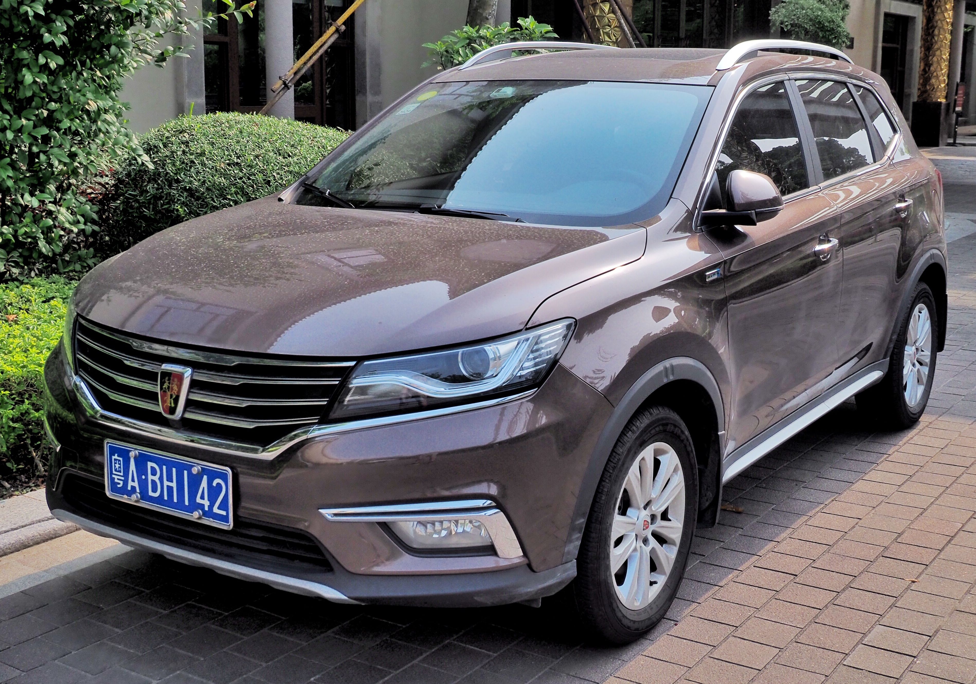 Brown Roewe RX5 compact SUV parked on a paved forecourt, front three-quarter view