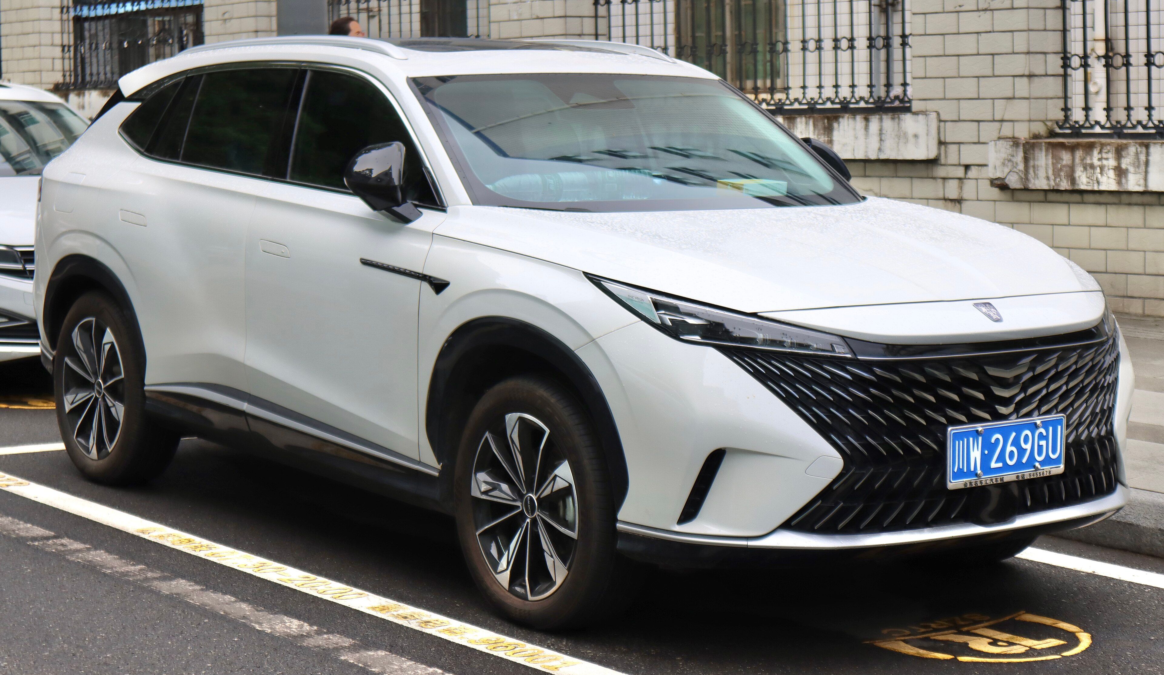 White second-generation Roewe RX5 SUV parked at a kerbside in China, front three-quarter view