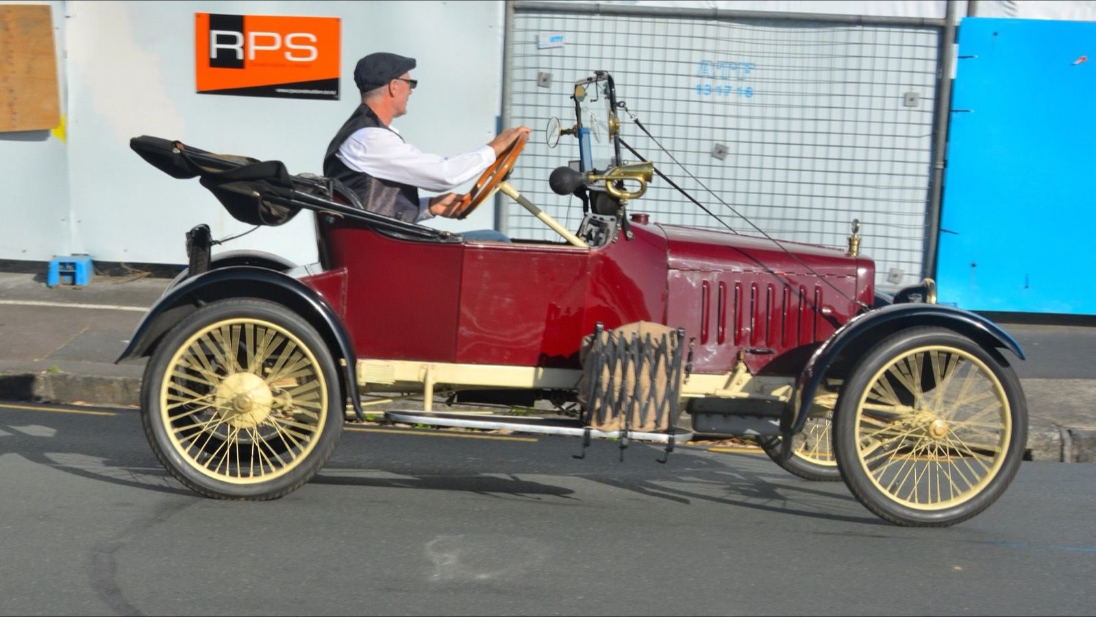 Maroon 1914 Saxon four-cylinder roadster, left side profile, being driven on a street