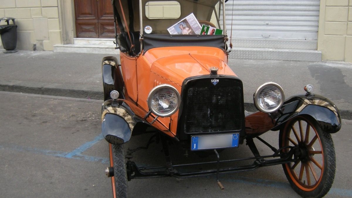 Orange Saxon four-cylinder runabout with folding top raised, front view, parked on a street