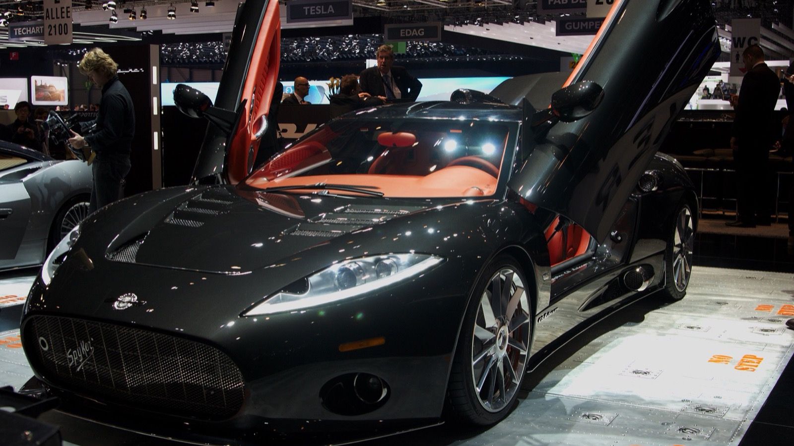 Black Spyker C8 Aileron with doors raised at the 2013 Geneva Motor Show, front three-quarter view