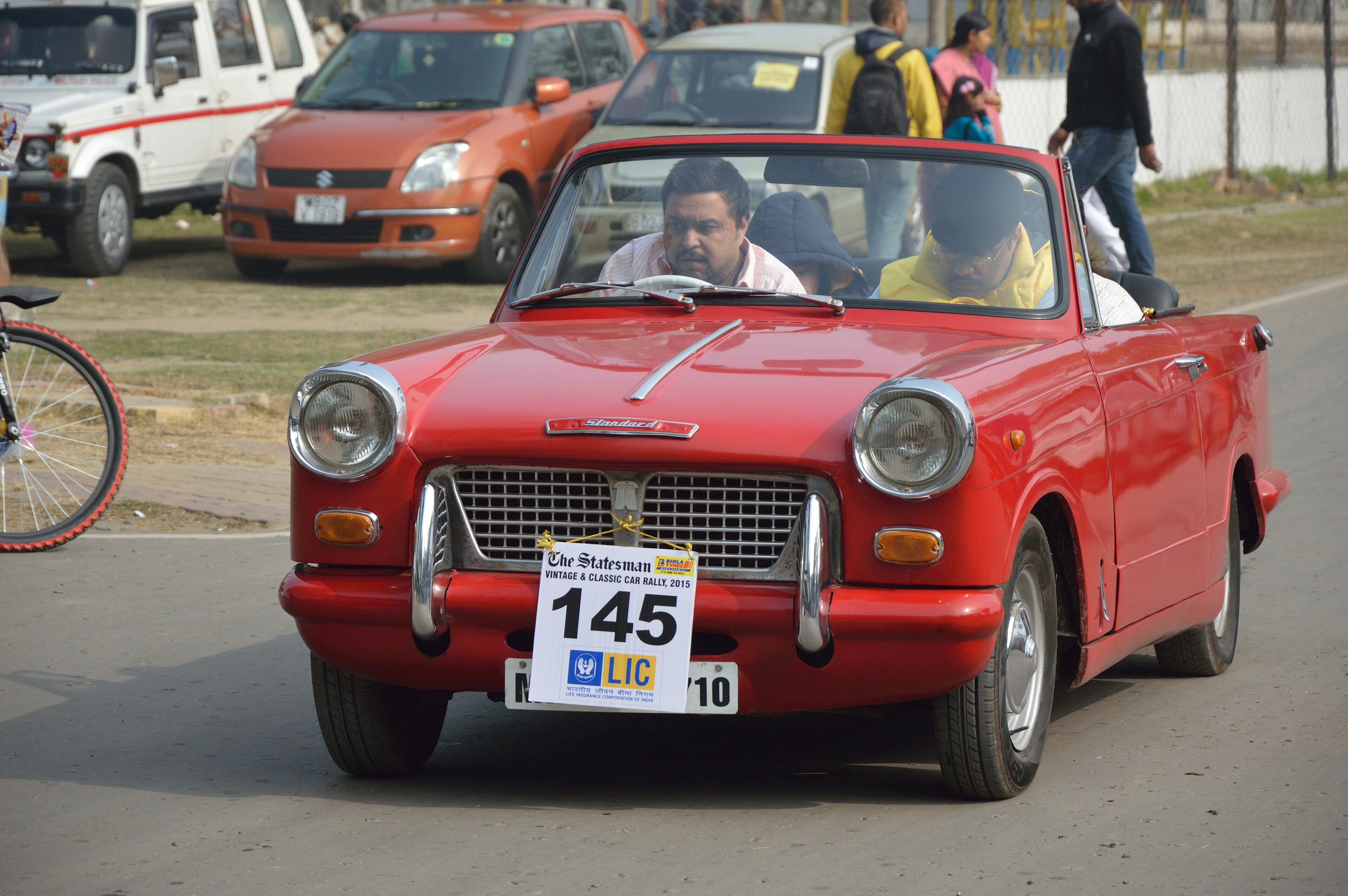 Red 1963 Standard Herald convertible at a Kolkata classic car rally, front three-quarter view