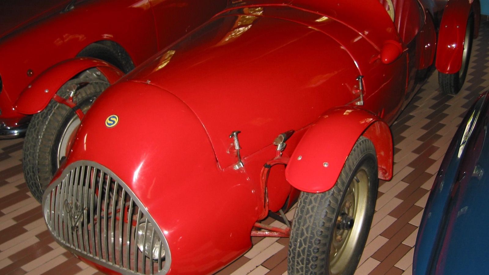Red cycle-fendered Stanguellini barchetta sports racer, front three-quarter view