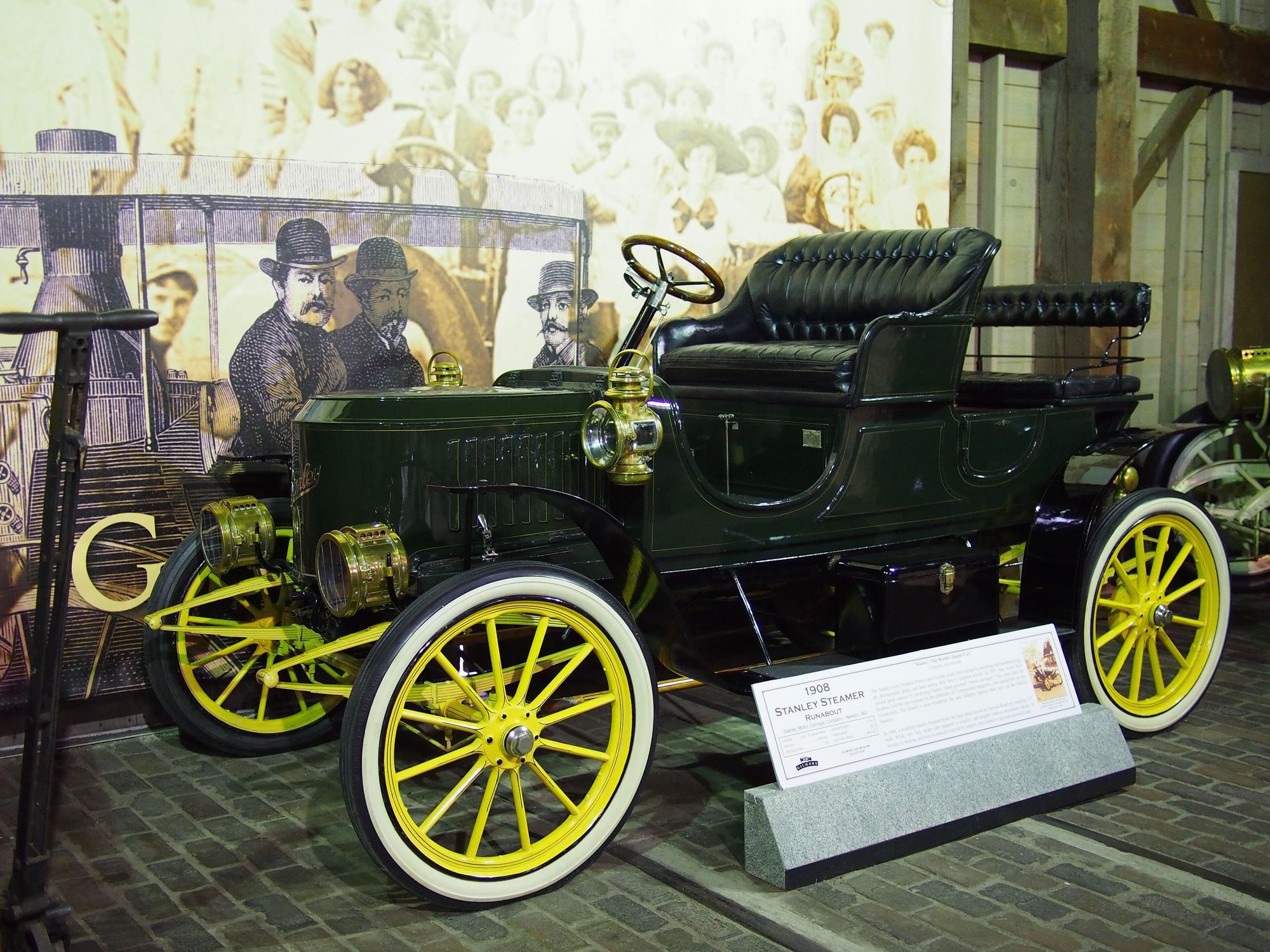 Dark green 1908 Stanley Steamer coffin-nose runabout with yellow wheels, front three-quarter view
