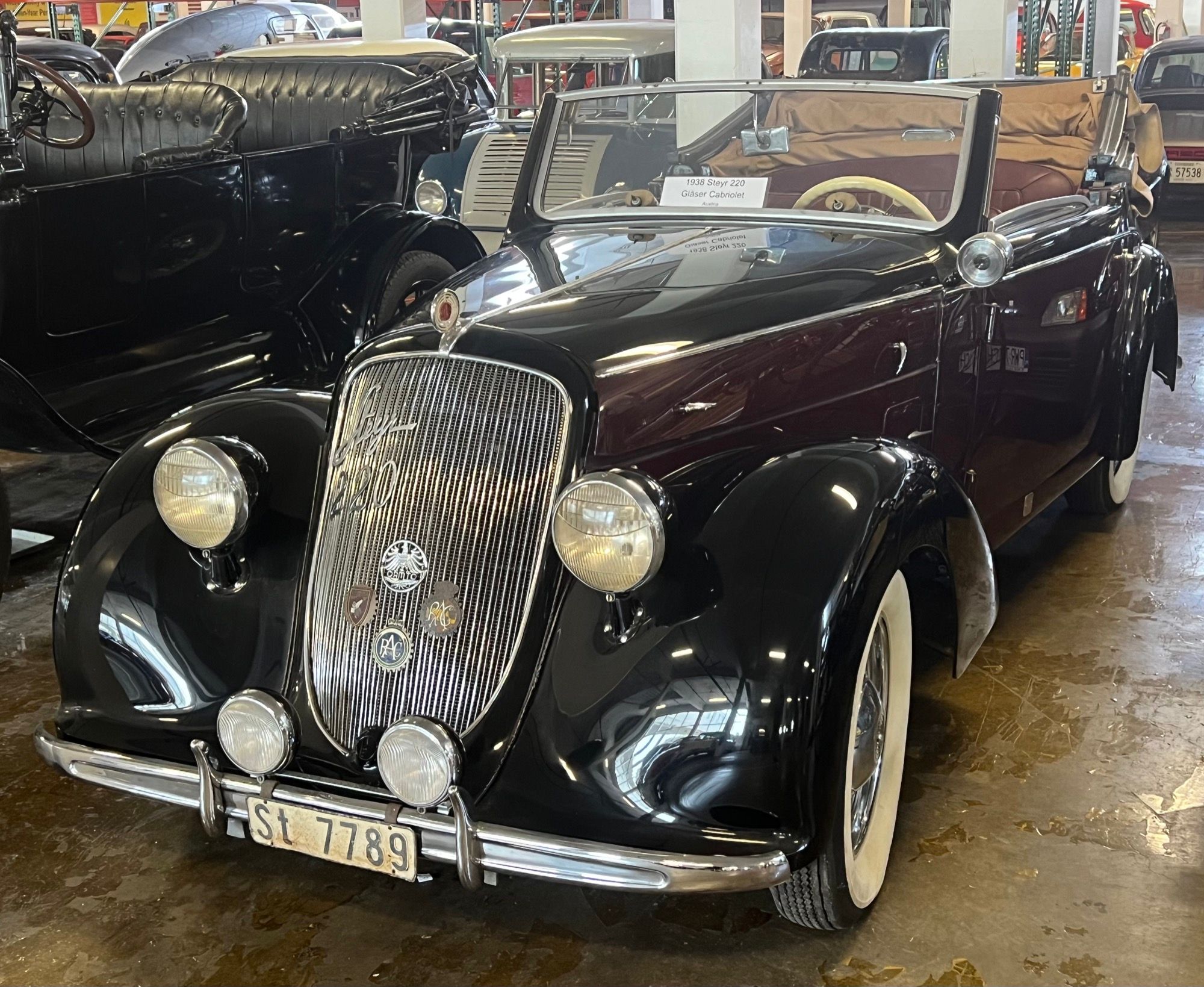 Black and maroon 1938 Steyr 220 Gläser Cabriolet on museum display, front three-quarter view