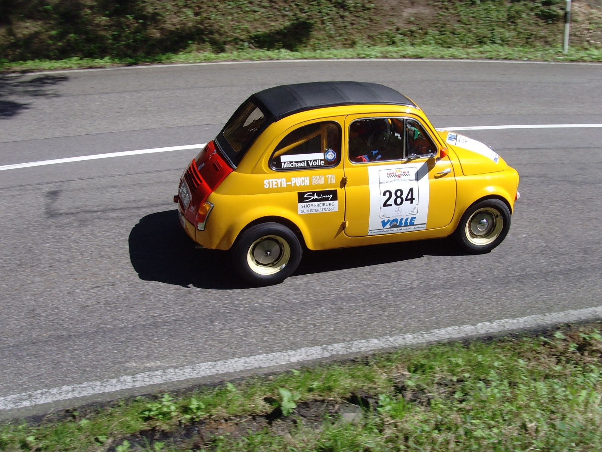 Yellow Steyr-Puch 650 TR rally car cornering on a mountain road, left side profile