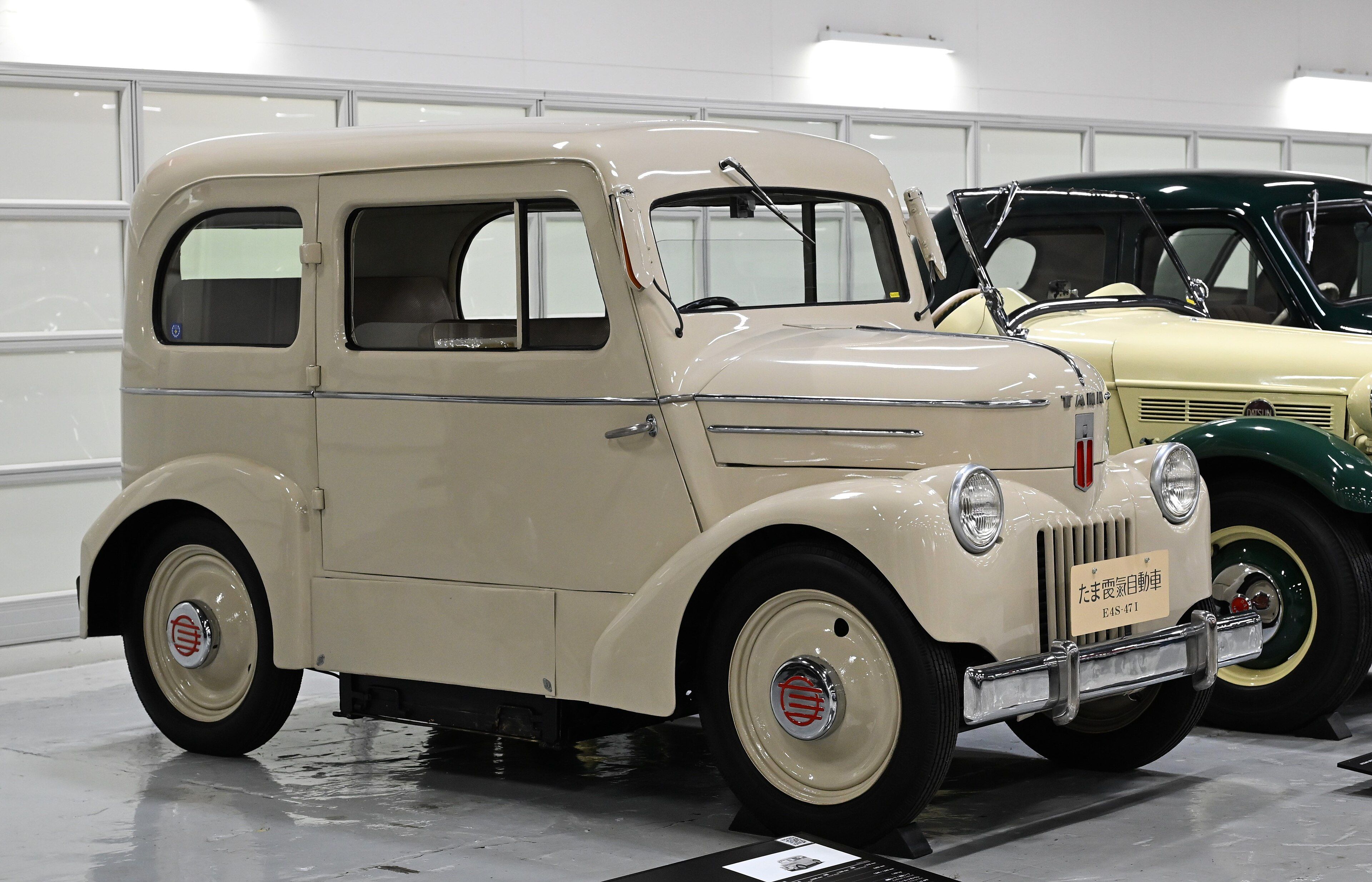 Cream 1947 Tama E4S-47 I electric sedan beside a Datsun, front three-quarter view