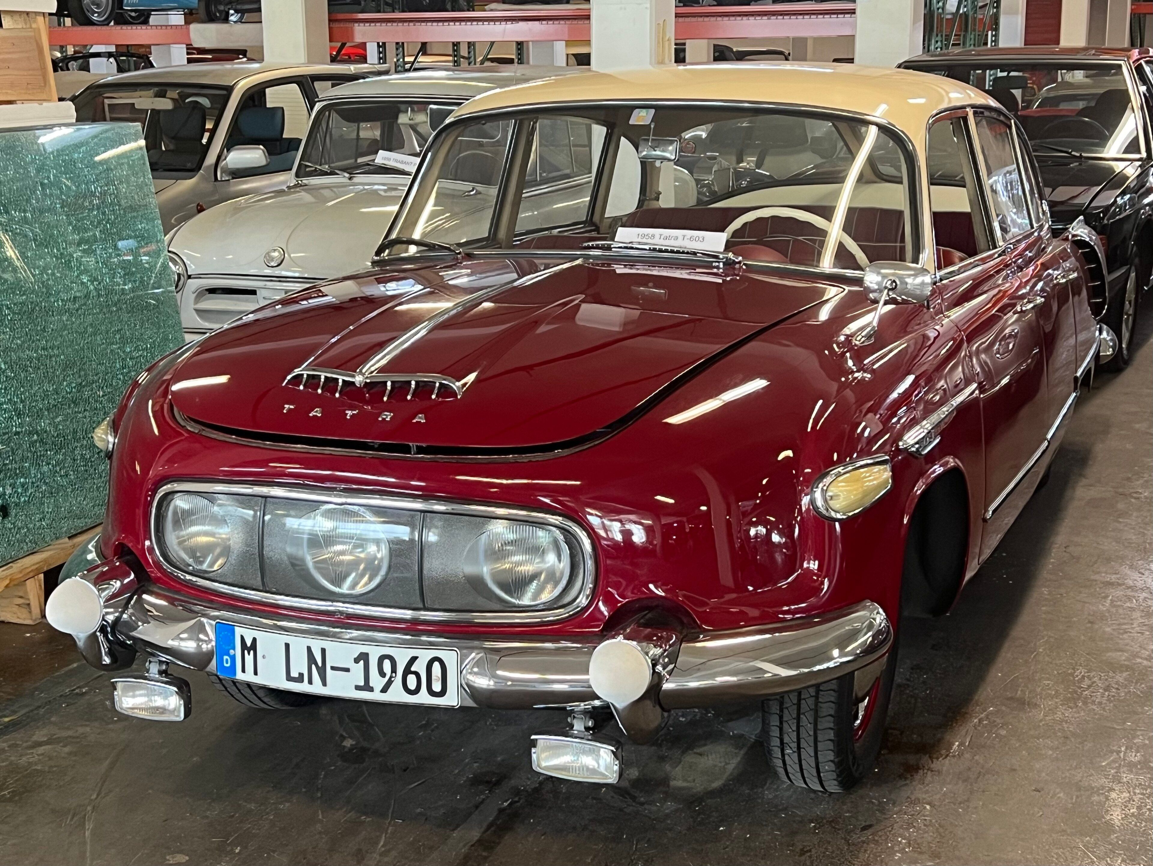 Maroon and cream 1958 Tatra 603 first series, front three-quarter view showing the three headlamps beneath a single glass cover