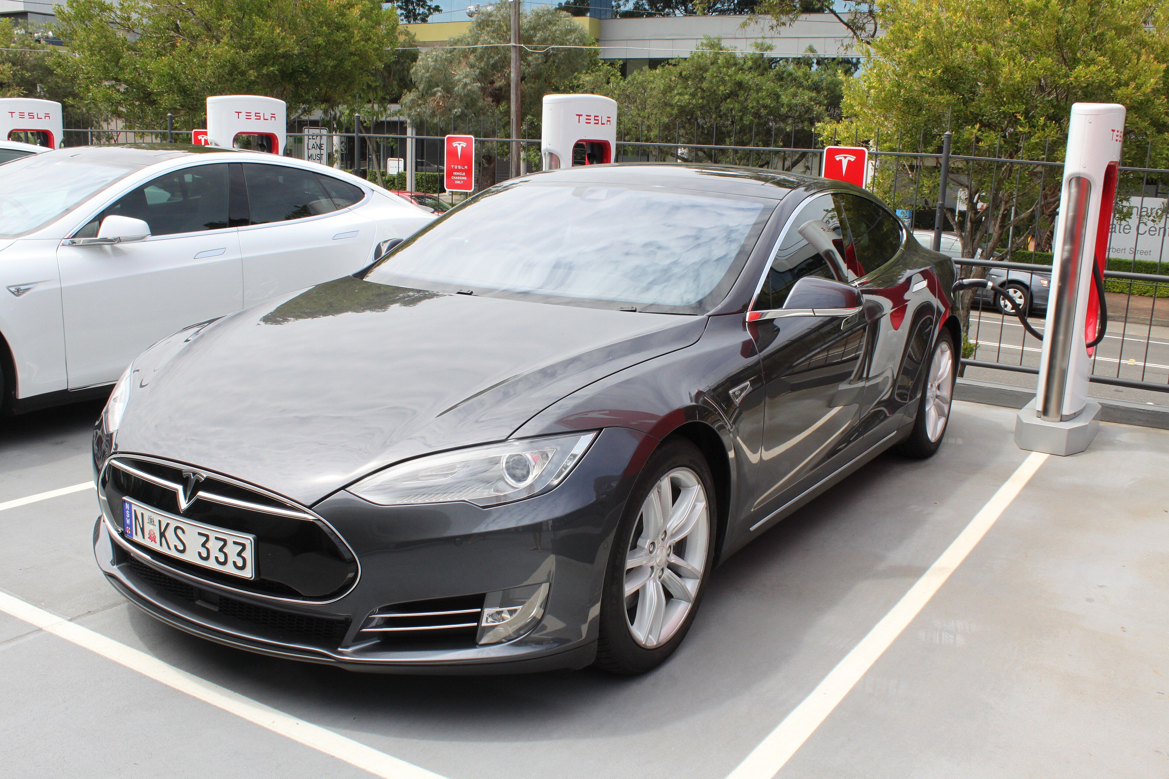Grey 2015 Tesla Model S at a Supercharger, front three-quarter view