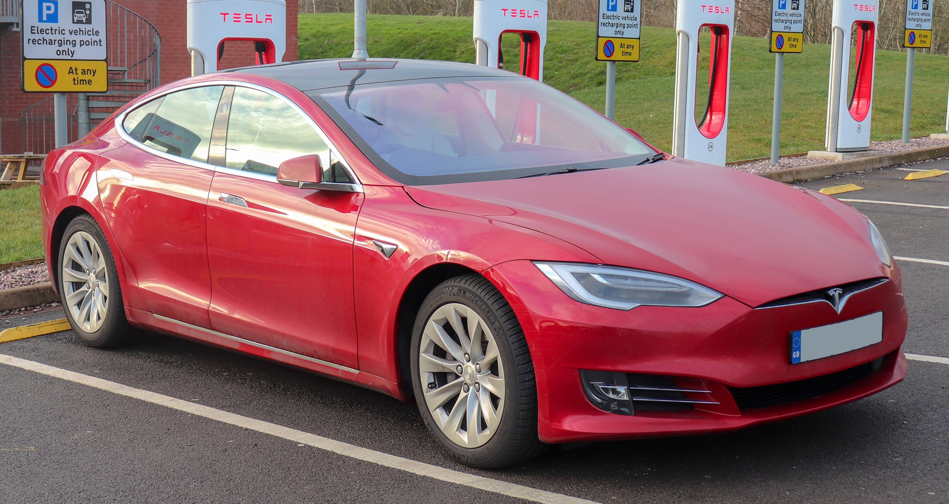 Red 2018 Tesla Model S 75D at a Supercharger, front three-quarter view